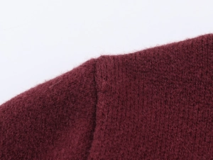 Détail de la couture d'épaule sur la veste en tricot bordeaux et texture du tissu