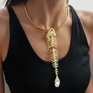 Close-up of a gold fishbone collar necklace with a white pearl pendant on a model