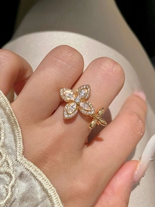 Detail of elegant gold flower ring with white zircons worn on model's finger