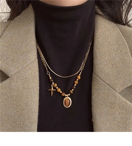 Close-up of double-layer stainless steel necklace with tiger eye beads and cross pendant