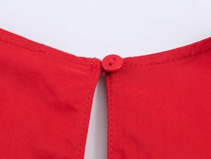 Vista dettagliata del tessuto in nylon rosso e della chiusura con bottone dell'abito midi