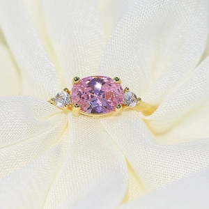 Detail of gold-plated ring featuring an oval pink zircon and brilliant side stones