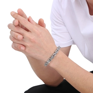 Detailed close-up of a silver Byzantine box chain bracelet on a male wrist in steel texture
