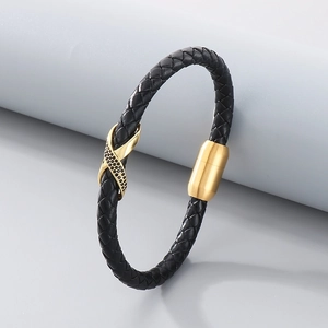 Detail of black woven leather bracelet with gold magnetic clasp and studded X charm