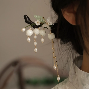 Détail d'épingle à cheveux fleur de lys blanc avec pompons dorés sur mannequin