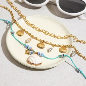 Bohemian gold shell necklace and blue beaded starfish pendant on a beach-themed background