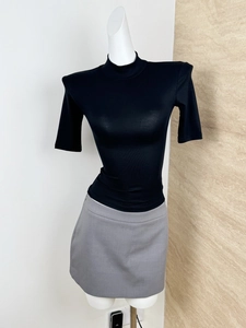 Detail view of black padded shoulder crop top and grey mini skirt on mannequin