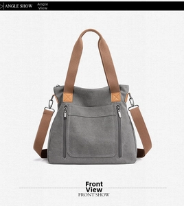 Front view of grey canvas tote bag with brown straps and functional zip pockets