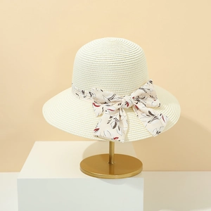 Dettaglio di un cappello di paglia crema a tesa larga con fiocco a fiori