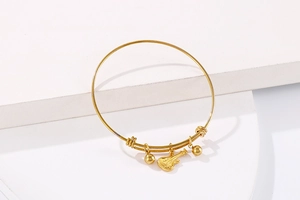 Detail of adjustable gold guitar charm bracelet on a geometric white display stand