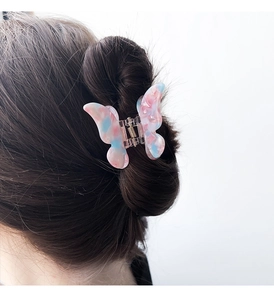Detail of pink and blue marble acetate butterfly hair claw clip worn on model's hair