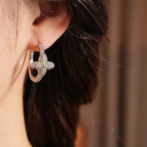 Detail view of silver clover hoop earrings with zircon stones on a female model