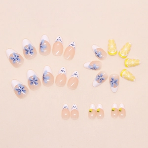 Detail of almond-shaped press-on nails with blue flowers and lemon patterns