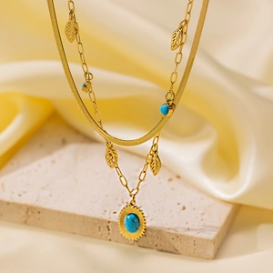 Detail of 18K gold-plated double-layer necklace with blue gemstone and sunburst pendant