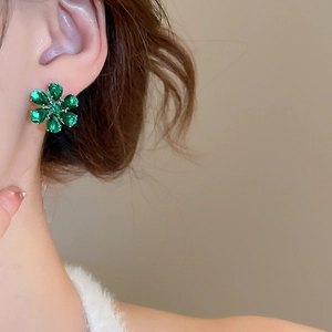 Detailed close-up of emerald green flower stud earrings with zircon petal settings