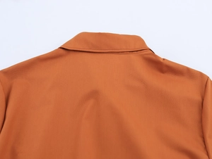 Vue détaillée du col de chemise orange et de l'empiècement dos avec coutures nettes