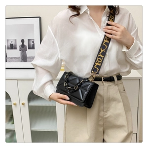 Detail of black quilted crossbody bag with textured pattern and decorative chain handle