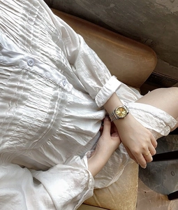 Close-up of business ladies' gold dial watch with two-tone steel strap on wrist