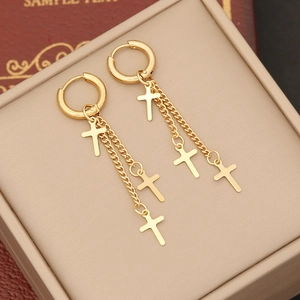 Detailed macro view of golden cross chain tassel earrings on a premium jewelry box