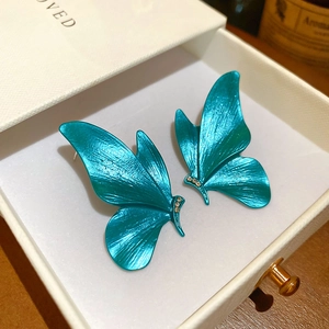 Macro view of teal butterfly earrings with sparkling crystals in a premium white gift box