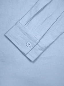 Close-up of light blue linen shirt cuff with white button and refined stitching details