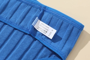 Detailaufnahme des Pflegeetiketts am blauen Ripp-String aus Baumwolle mit Größe