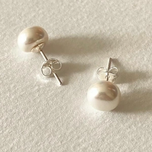 Elegant 925 silver stud earrings with round white freshwater pearls on beige backdrop