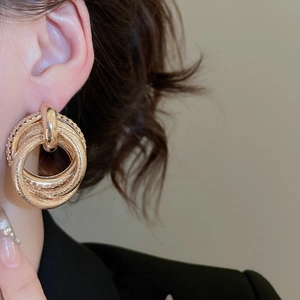 Detailed view of layered gold hoop earrings with polished and frosted metal textures