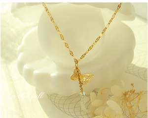 Detail of gold butterfly pendant with tassel bead on a thin chain in an elegant setup