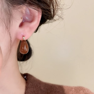Gros plan d'une boucle d'oreille goutte marron chocolat brillante et fermoir doré