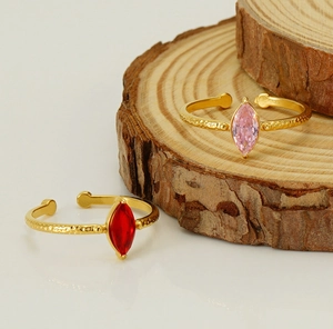 Dettaglio degli anelli dorati con texture martellata e pietre taglio marquise rosso e rosa