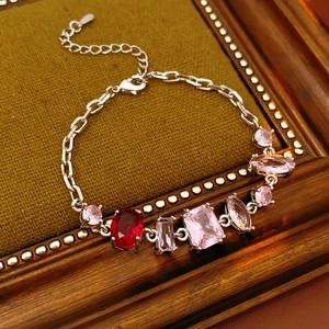 Macro shot of French vintage silver bracelet with pink and red zircon stones on green velvet