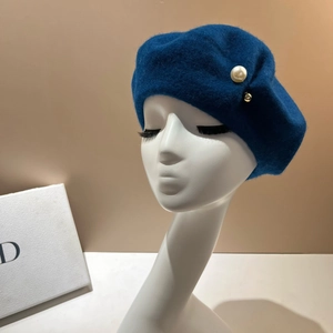 Detailed texture of navy wool beret featuring a large pearl and gold bead accent