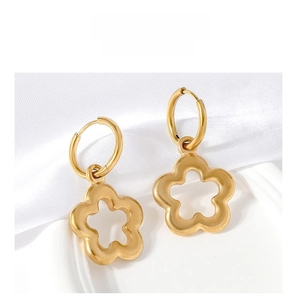 Detail of gold floral dangle earrings featuring hollow five-petal flower on satin