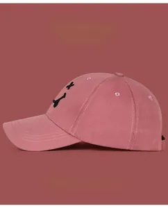 Détail de la casquette de baseball rose en coton avec smiley noir brodé sur le côté