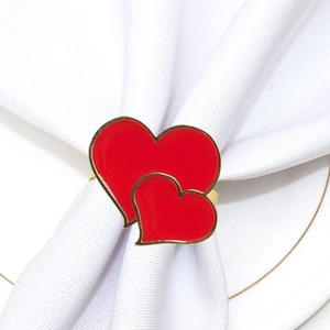 Detail of red enamel double heart napkin ring with gold trim on white napkin