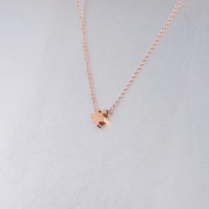 Macro shot of rose gold puzzle piece pendant with polished finish on a fine chain