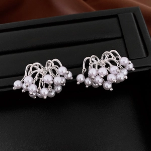 Detailed view of silver curved tassel earrings with clusters of white round pearls