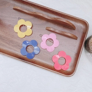 Set of four colorful matte resin flower hair clips in pink, blue, yellow, and coral red