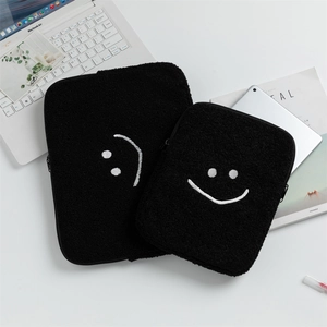 Détail de la housse d'ordinateur en peluche damier avec un smiley brodé et une fermeture