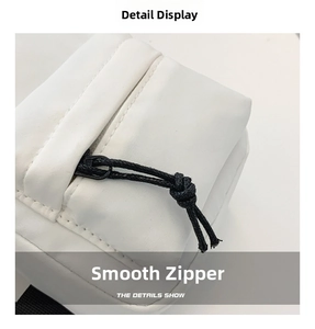 Detail of smooth black zipper and nylon fabric on a white crossbody bag