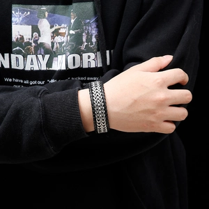 Close-up of men's braided black leather bracelet with silver metal chain on wrist