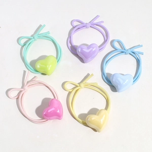 Detailed flat lay of colorful flower hair ties with heart and bow charms on white background