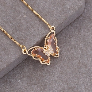 Macro view of a 18K gold butterfly necklace with peach gemstone wings and crystals