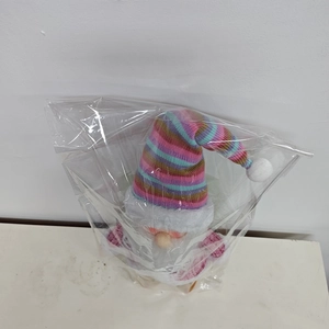 Detail view of colorful knit plush Christmas gnome dolls in transparent protective packaging