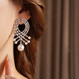 Détail de boucles d'oreilles argentées avec cristaux et grandes perles pendantes
