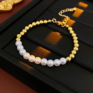 Dettaglio di un bracciale di perle di lusso con sfere dorate su portagioie nero