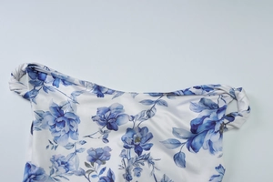 Detail of blue floral print on white dress showing shoulder knot and soft fabric texture
