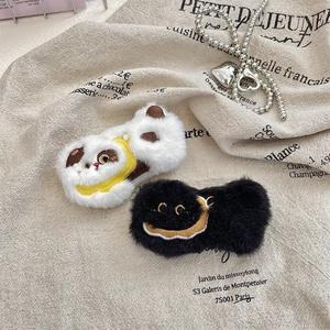 Detail of plush animal and crescent moon brooches on a neutral linen fabric background