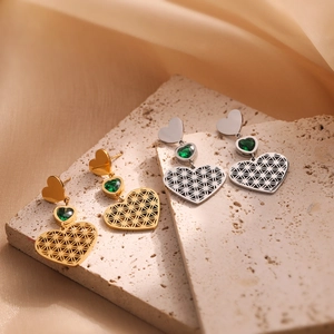 Hollow heart earrings in gold and silver steel featuring a small green gemstone